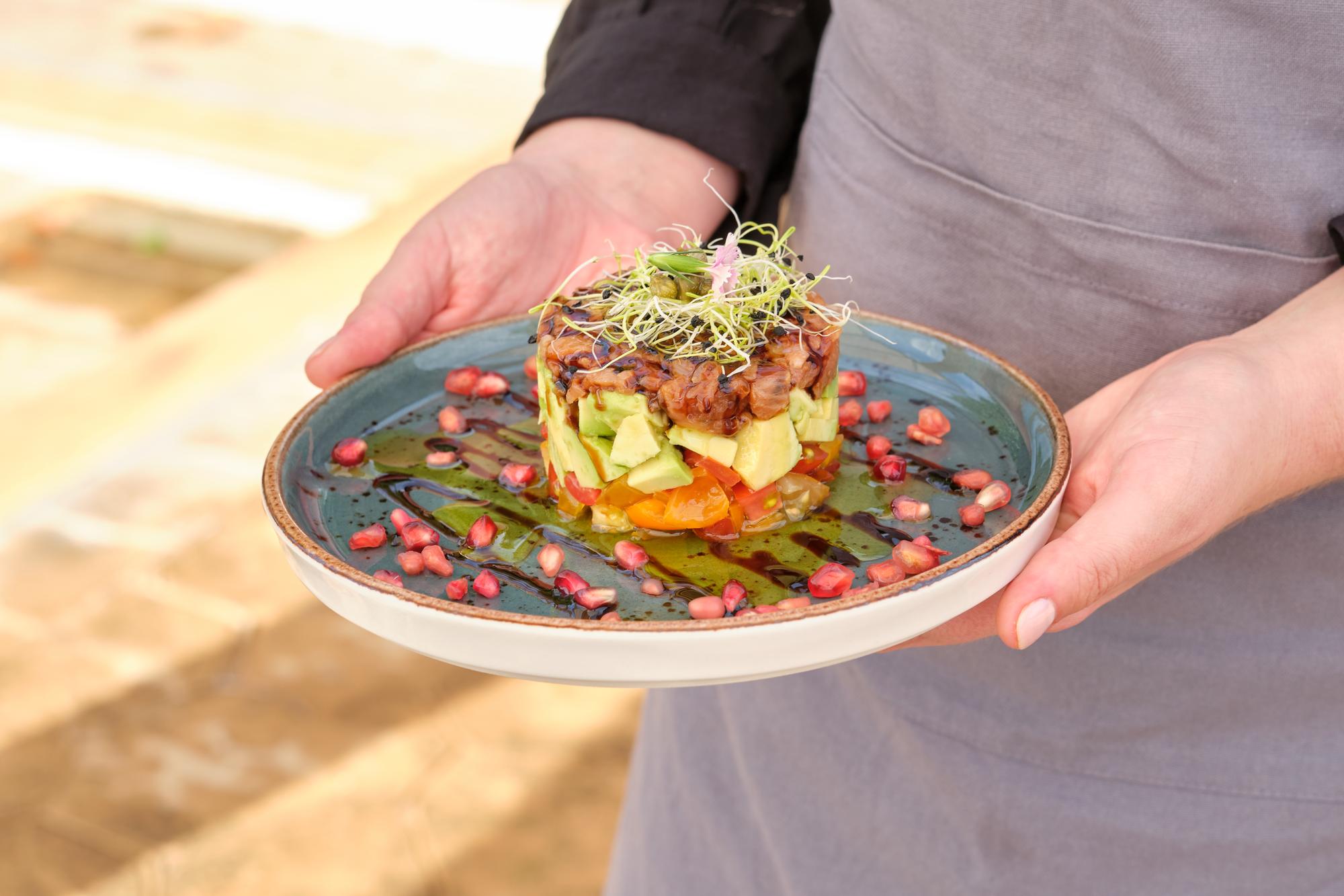 Chef arranging a simple plated dish on a wooden table